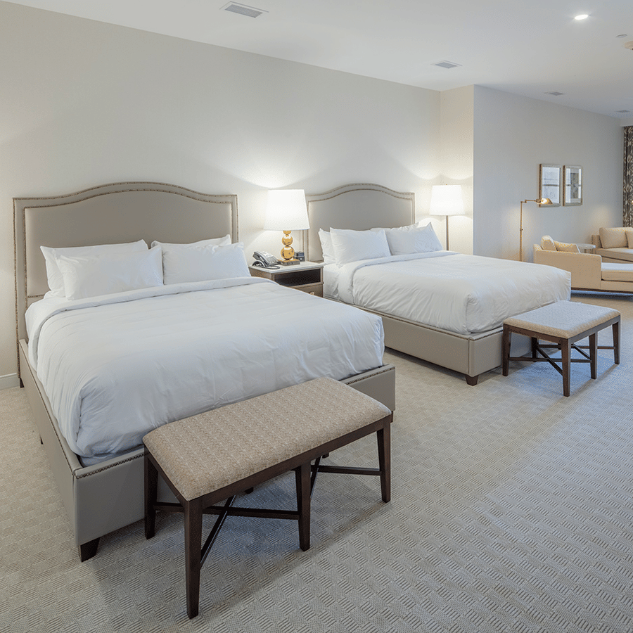 Lakeview Double King Room featuring plush beds next to each other with ottomans and a sitting space next to the window
