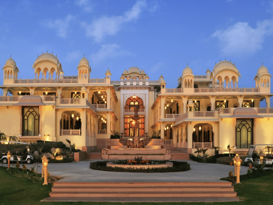 Facade of Rajasthali Resort & Spa Jaipur with plants in front and a clear sky in the background.