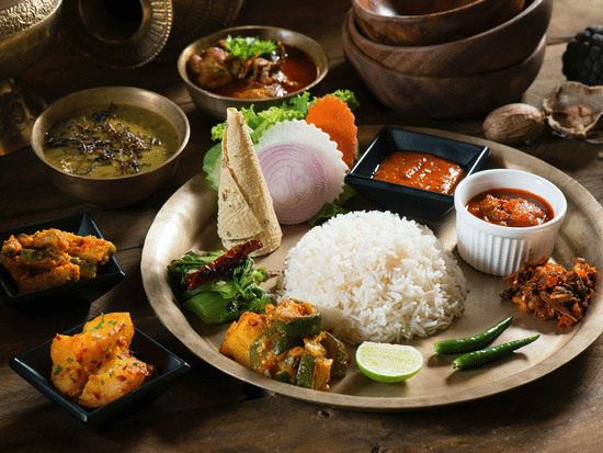 a full course nepali meal with neatly served rice, dal, curries and other vegetable sabzi garnished with green chilly and lemon