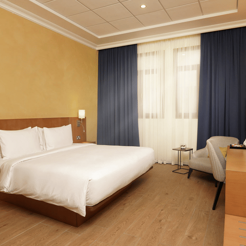 a king bed with side tables and lamps inside Classic King Room - La Maison Hotel, Doha