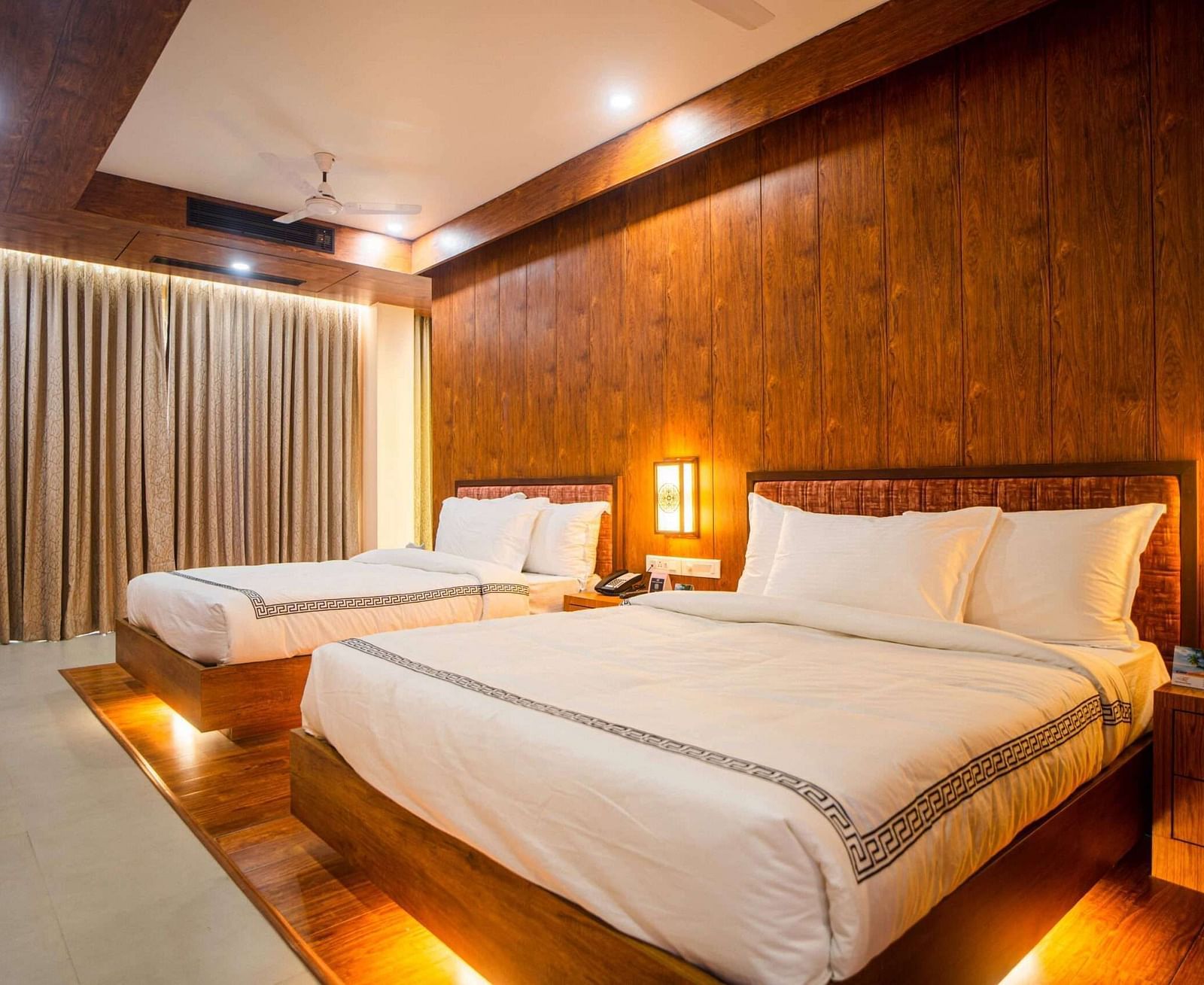 The comfortable rooms at Mansha Palace offer two beds, warm wooden accents, and a strategically placed opening that provides a peek into the bathroom.