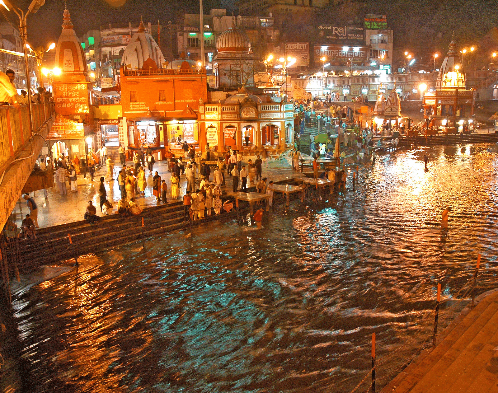 The image features a wide angle view of illuminated city with a lake in the night