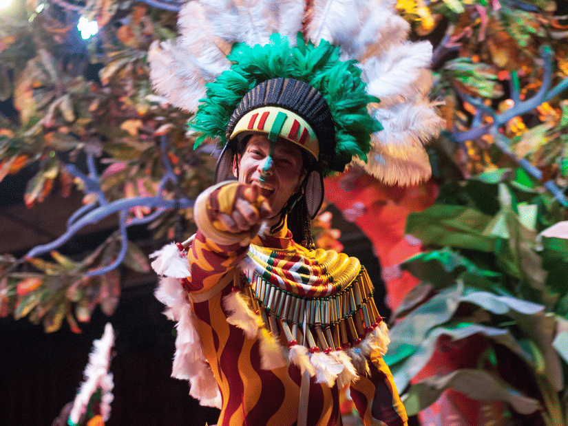 A person in a colorful carnival costume withA person wearing a colorful carnival costume with a large green feathered headdress during a festive parade a large green feathered headdress, participating in a festive parade