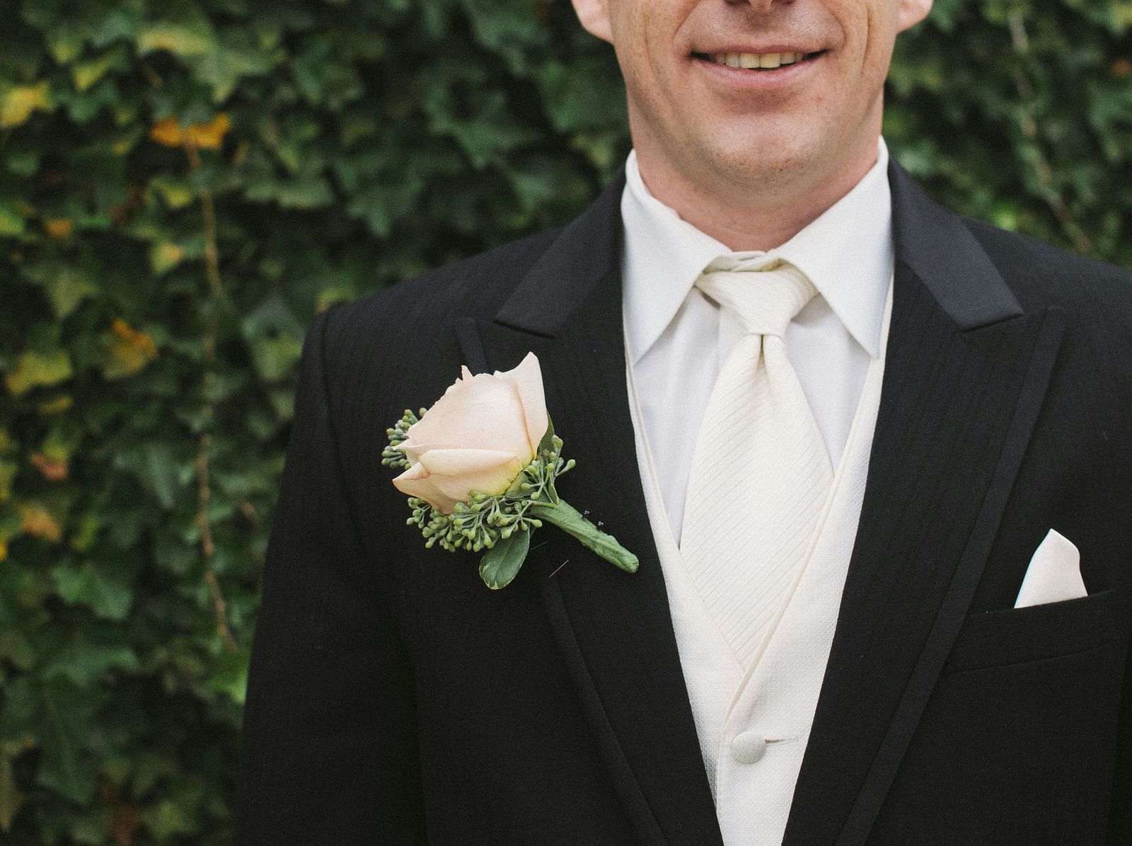 A groom with a white rose pinned to his suite