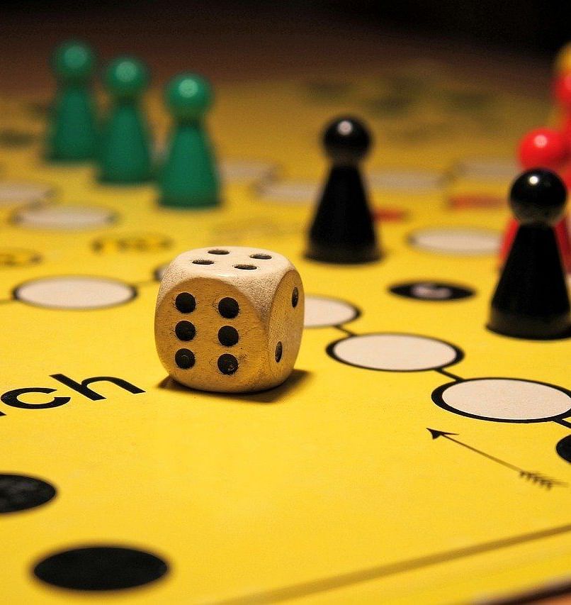 An image of a ludo game with tokens and a dice