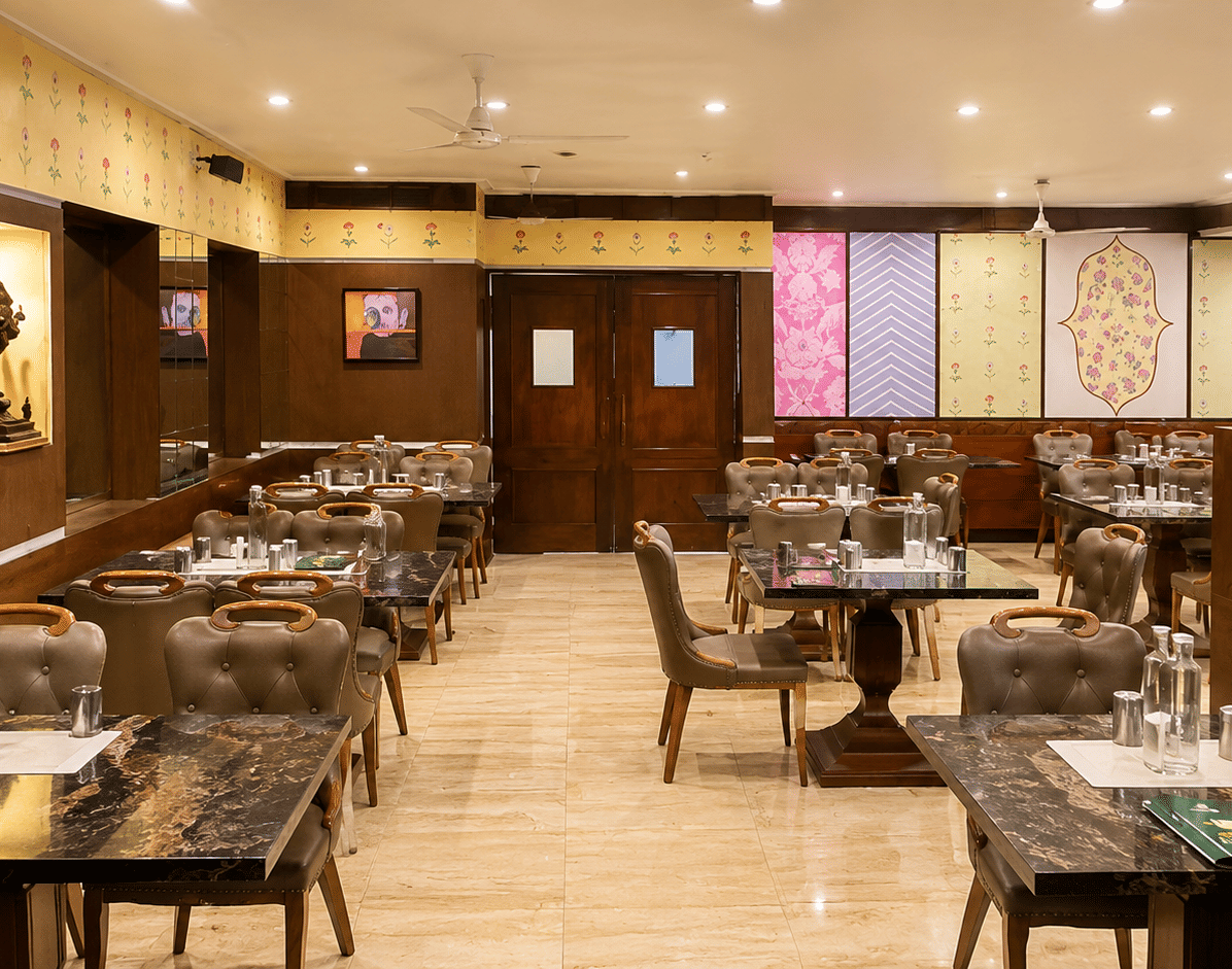 Super Snax restaurant with granite-topped tables, upholstered chairs, floral wall motifs, patterned panels and a tiled floor at MAYFAIR Garden, Rourkela.