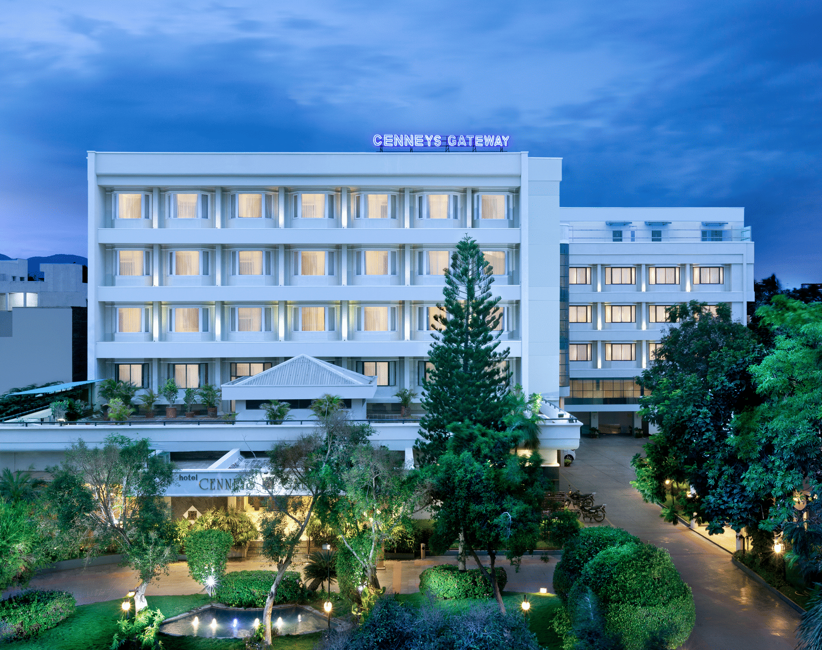 A facade view of Cenneys Gateway against the sky, surrounded by trees and plants in the front.