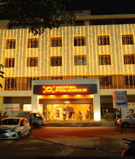 The exterior of Max Hotel Prayagraj during the night with cars parked in front of the building.