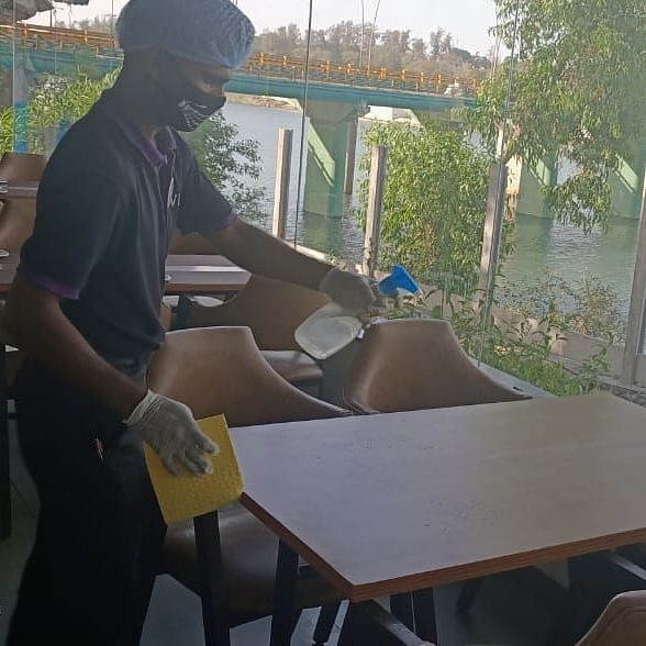 a staff member cleaning the table inside the restaurant at one of the hotels - VITS Hotels & Resorts