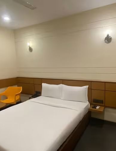 View of a hotel room with two single beds, a wooden table, and minimal decor - Max Hotel Prayagraj