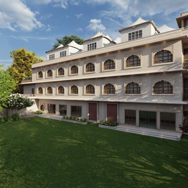 A 3-storey building with repetitive arched balconies and a corner tower feature, overlooking a wide landscaped lawn with trees and shrubs, shown as an architectural visualisation at Ananta Elite Bharatpur.