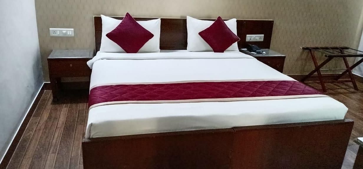 A clean and inviting bed with crisp white and red linen promises a comfortable night's sleep at Lords Midtown Suites.