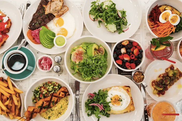  Top view of a spread of food with various dishes and edibles on white plates. 