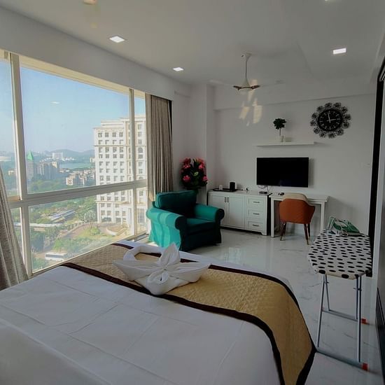 suite room at Maxxvalue Hotel, Chitranjan Tower, Powai with pristine white lines and wide windows offering city view and other room amenities