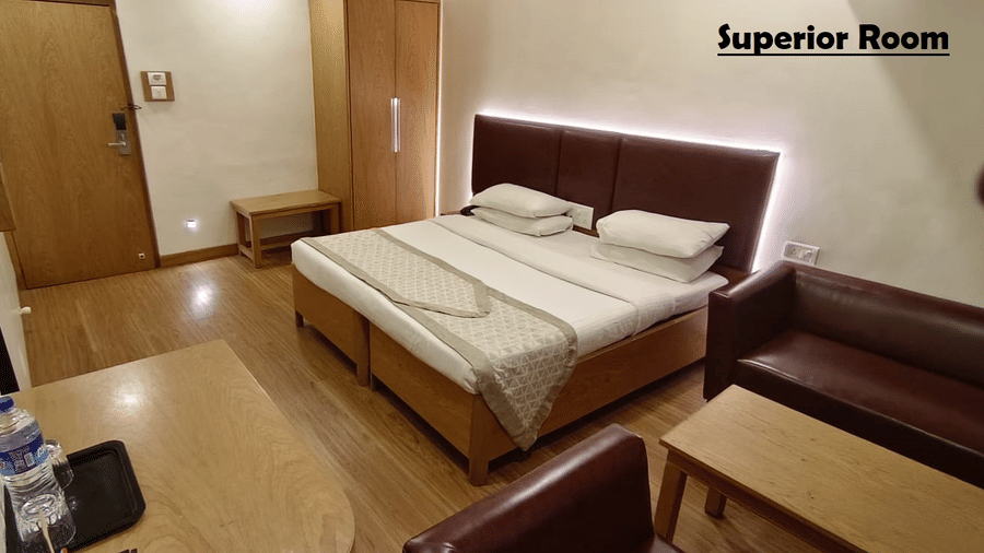 A bedroom featuring a neatly-made bed with a patterned runner, a wooden closet, and a sitting area | Kings International Juhu