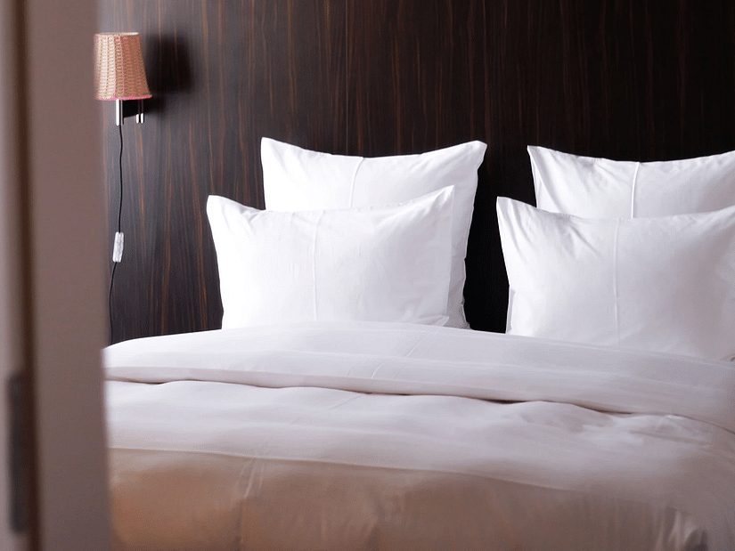 A close up shot of a bed in a hotel room with plush pillows and a wall-mounted light - S Hotel Kingston, Jamaica