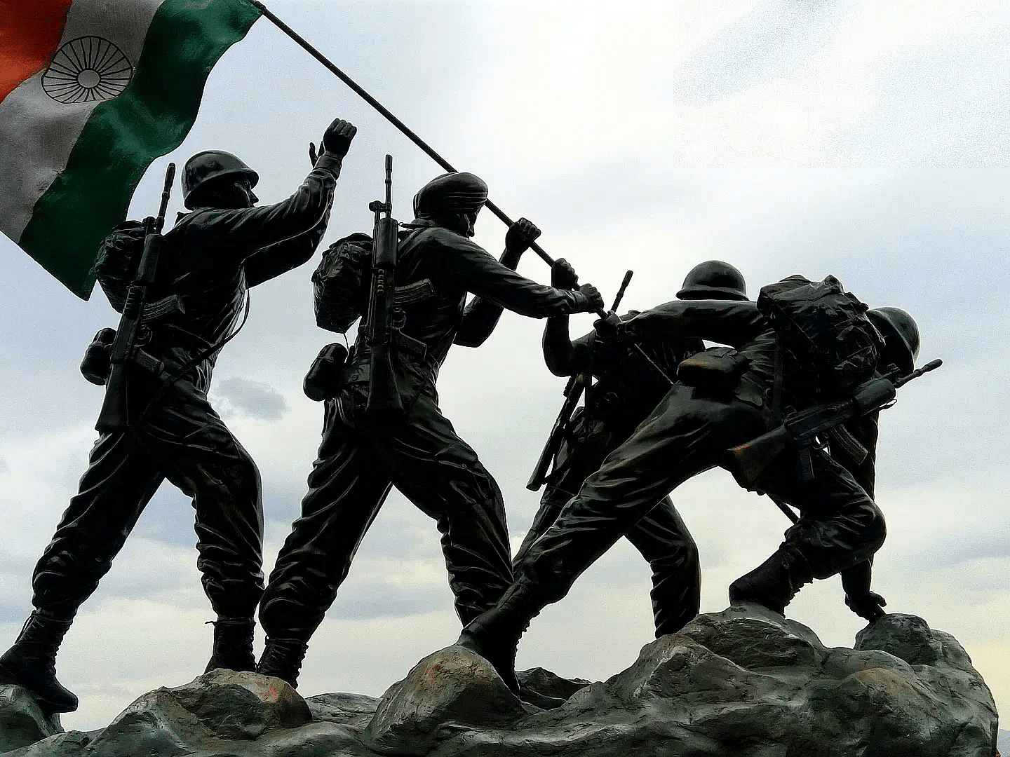 Four soldiers standing on a rock waving the Indian Flag wcrajy