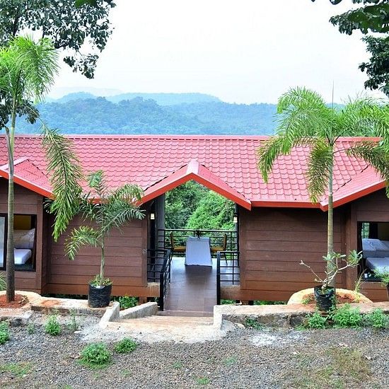 Riverview Luxury Cabin Exterior - Twin red-roofed wooden cabins in a forest setting with a mountain backdrop.