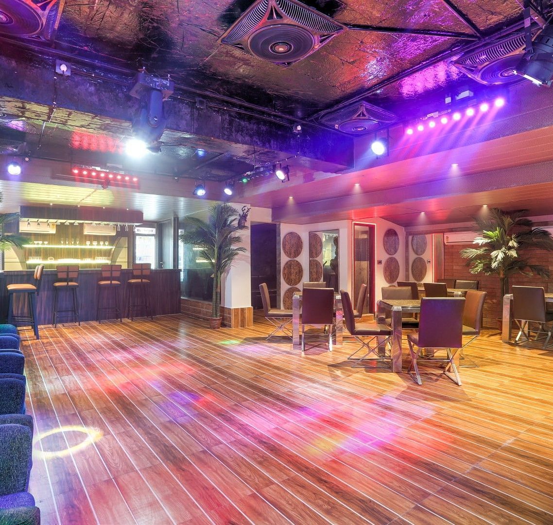  Dining area adorned with vibrant lighting and featuring comfortable cushioned seating