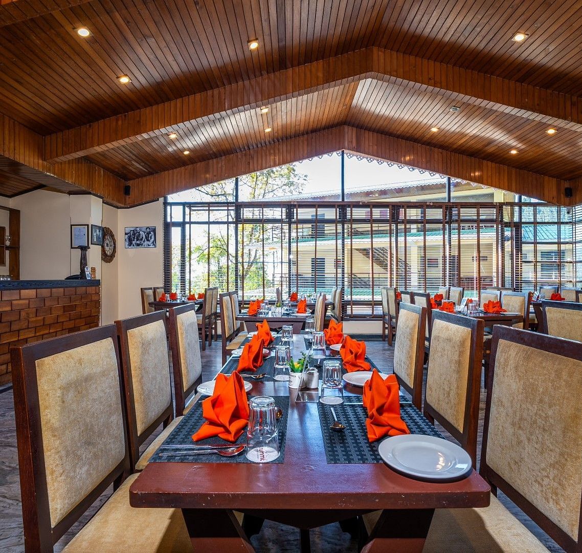 Restaurant & Bar - Tsomgo offers a very spacious dining area with tables, chairs, and culinary aesthetics elegantly arranged on each table at Summit Norling Resort & Spa, Gangtok.