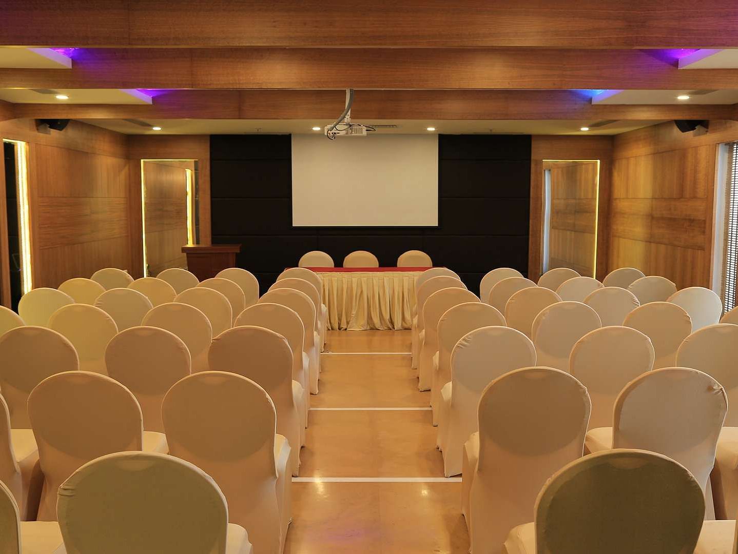 Overview of Tulip Hall at Dhanalakshmi Srinivasan Hotels, Perambalur with chairs arranged in theater style seating  and warm lighting