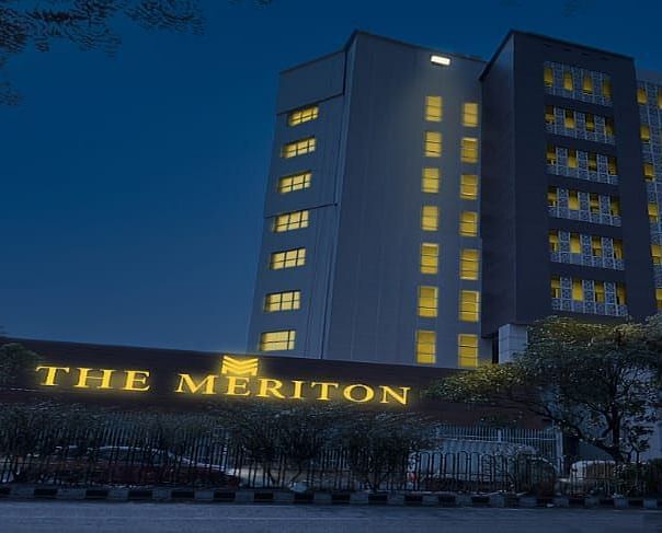 Facade shot of The Meriton in New Delhi during the night time with a well illuminated neon board in the front.