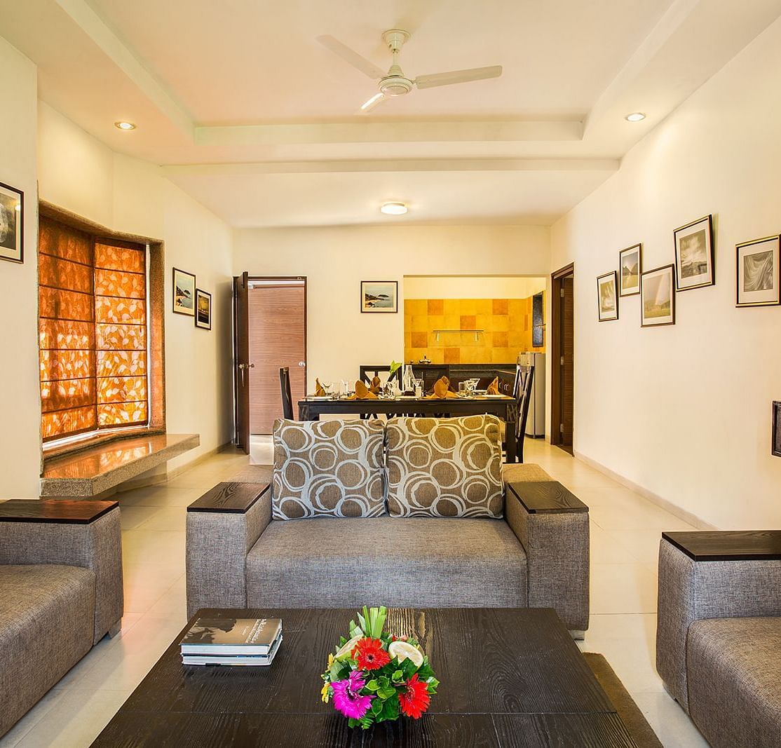 An image of a seating area with photos hanged on the wall, flat TV screen,  and behind the seating area there is a dining table set - The Riverview Retreat, Corbett
