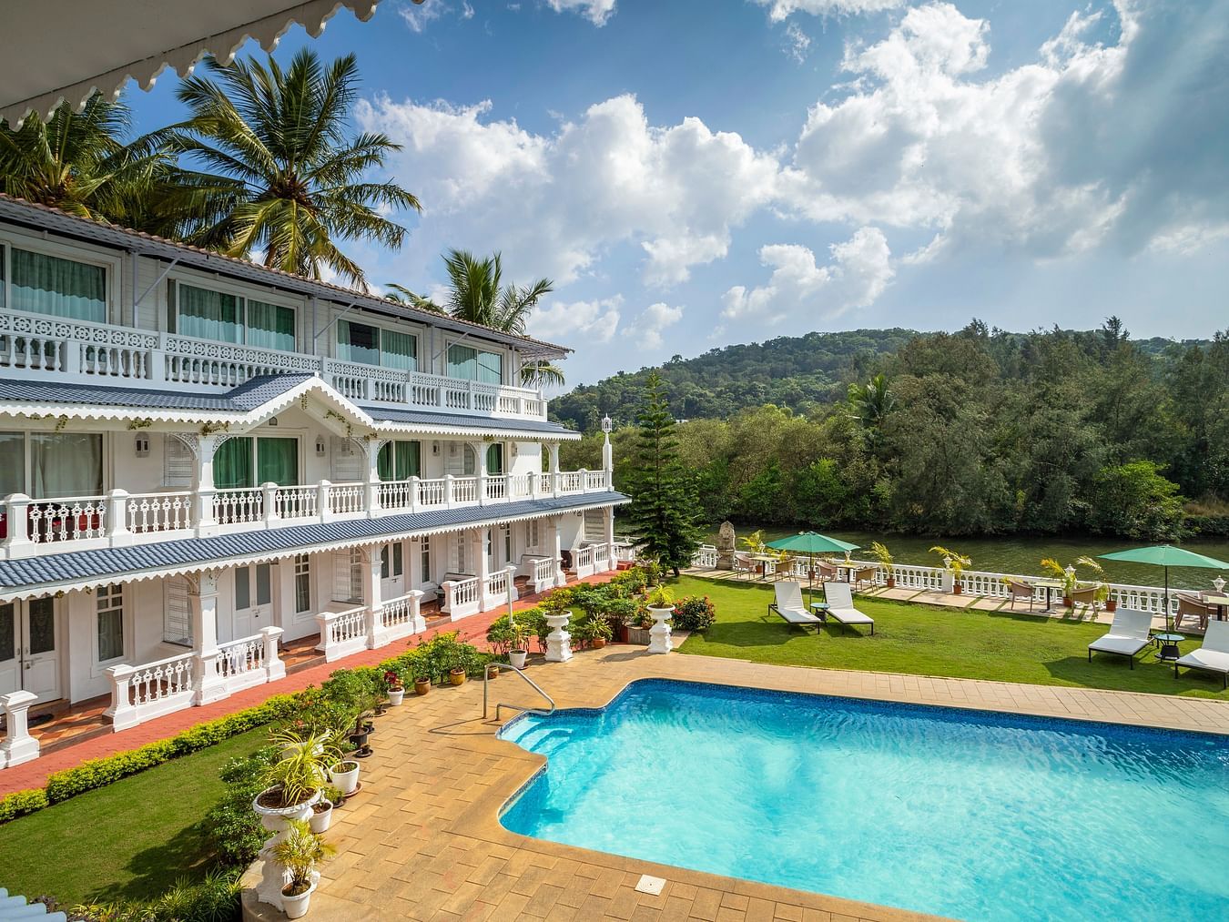 The facade of the hotel alongside the pool - Stone Wood Riverfront Resort, Siolim