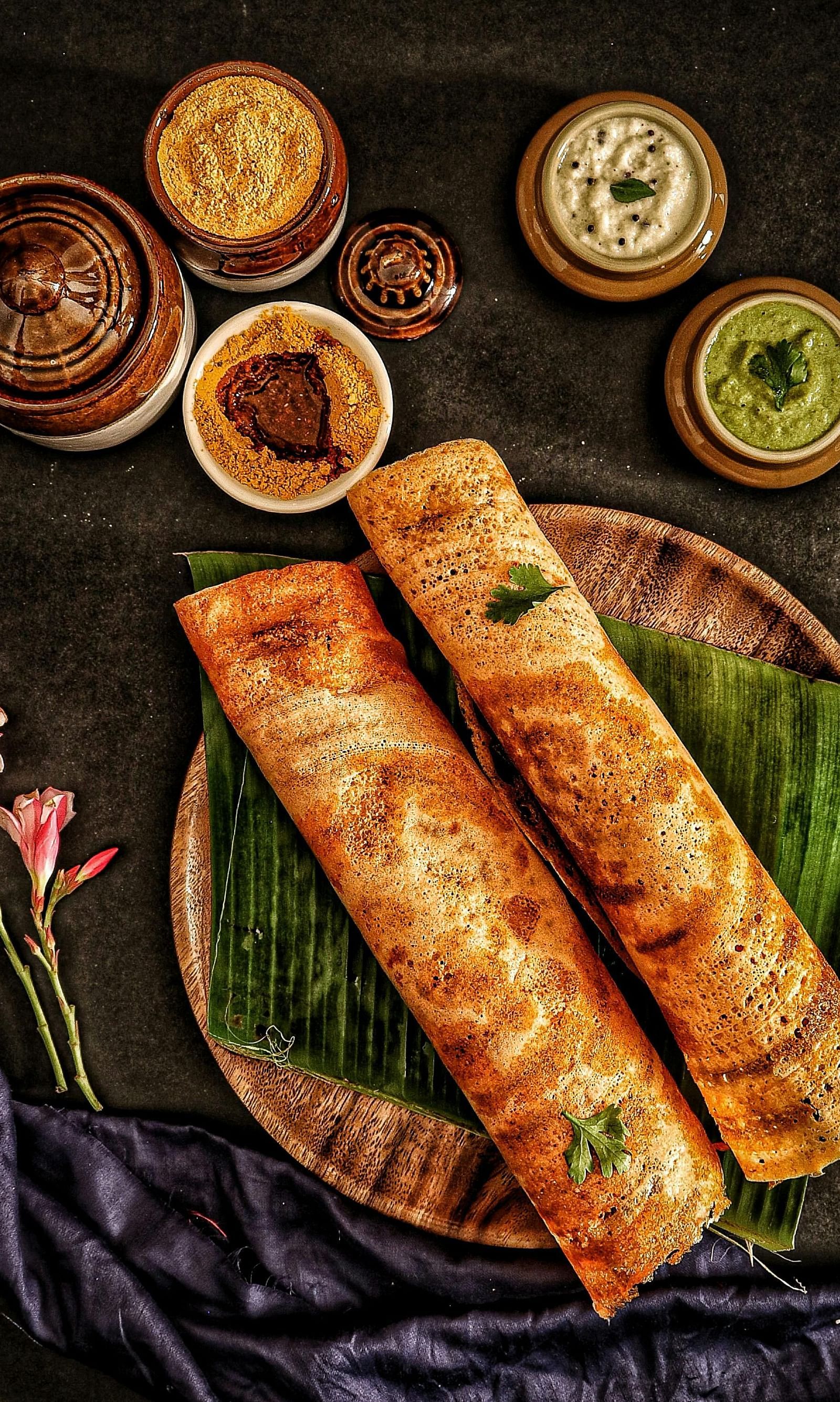 A South Indian dosa is served with bowls of chutney alongside it.