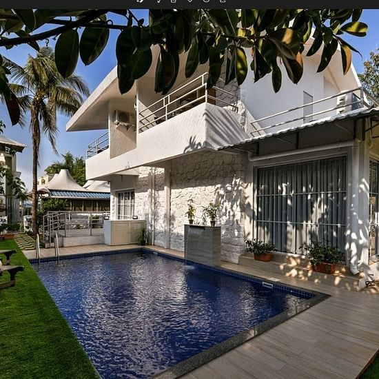 A breathtaking view of a Maxxvalue Klub Klass Villa, Lonavala featuring a stunning infinity pool, lush gardens, and modern architectural design.