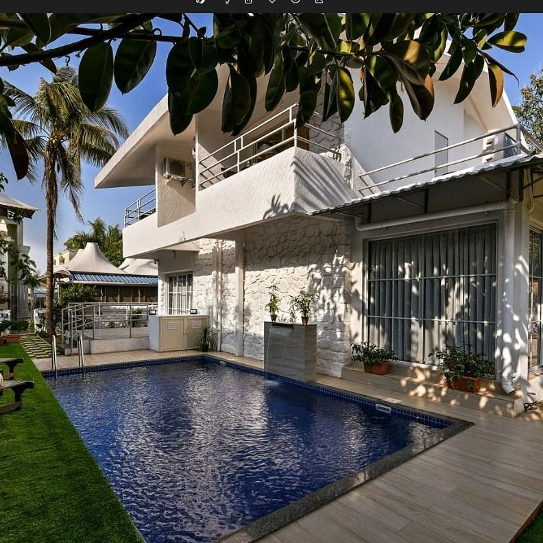 A breathtaking view of a Maxxvalue Klub Klass Villa, Lonavala featuring a stunning infinity pool, lush gardens, and modern architectural design.
