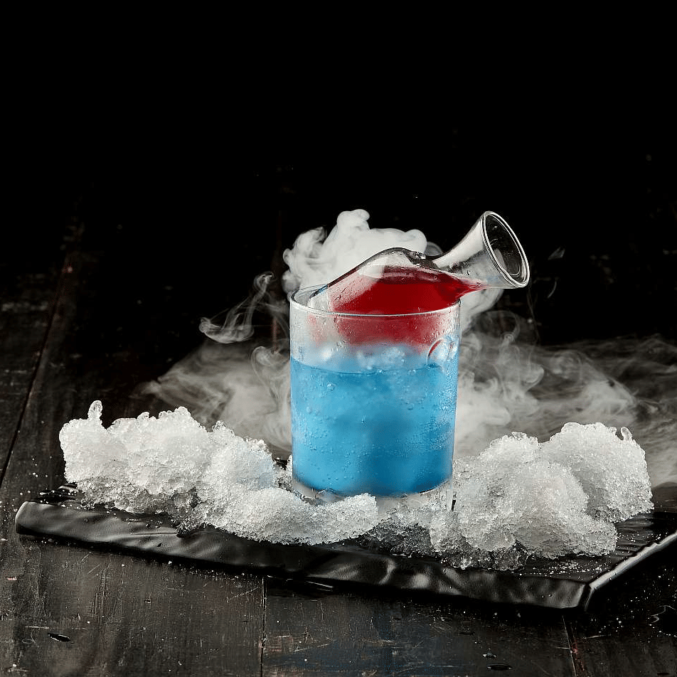 A vibrant blue cocktail with dry ice, served on a dark surface - The Citrine