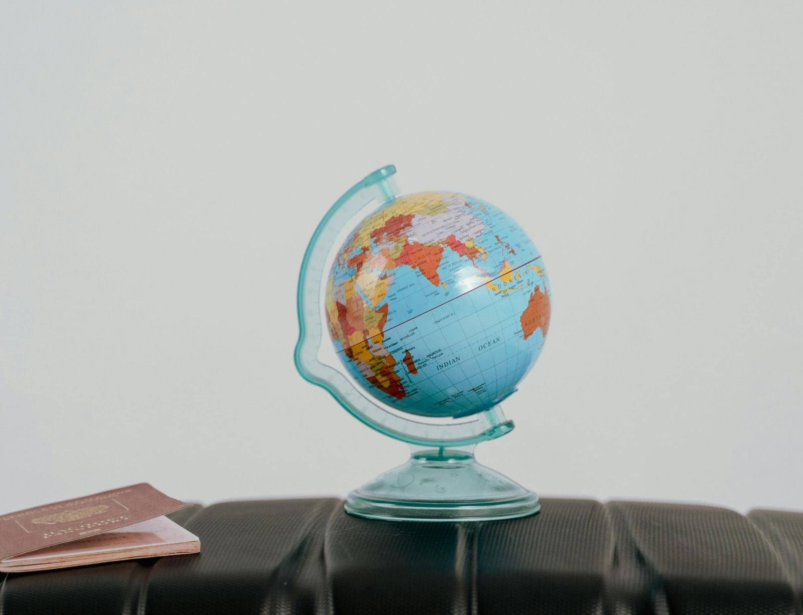 A small globe placed on top of a suitcase beside two passports, symbolising travel and exploration.