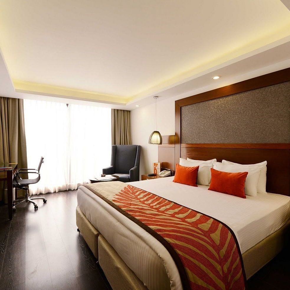Deluxe Room at The Cunningham Hotel featuring a with a king size bed, warm lighting, wooden accents, a workspace, and a seating area