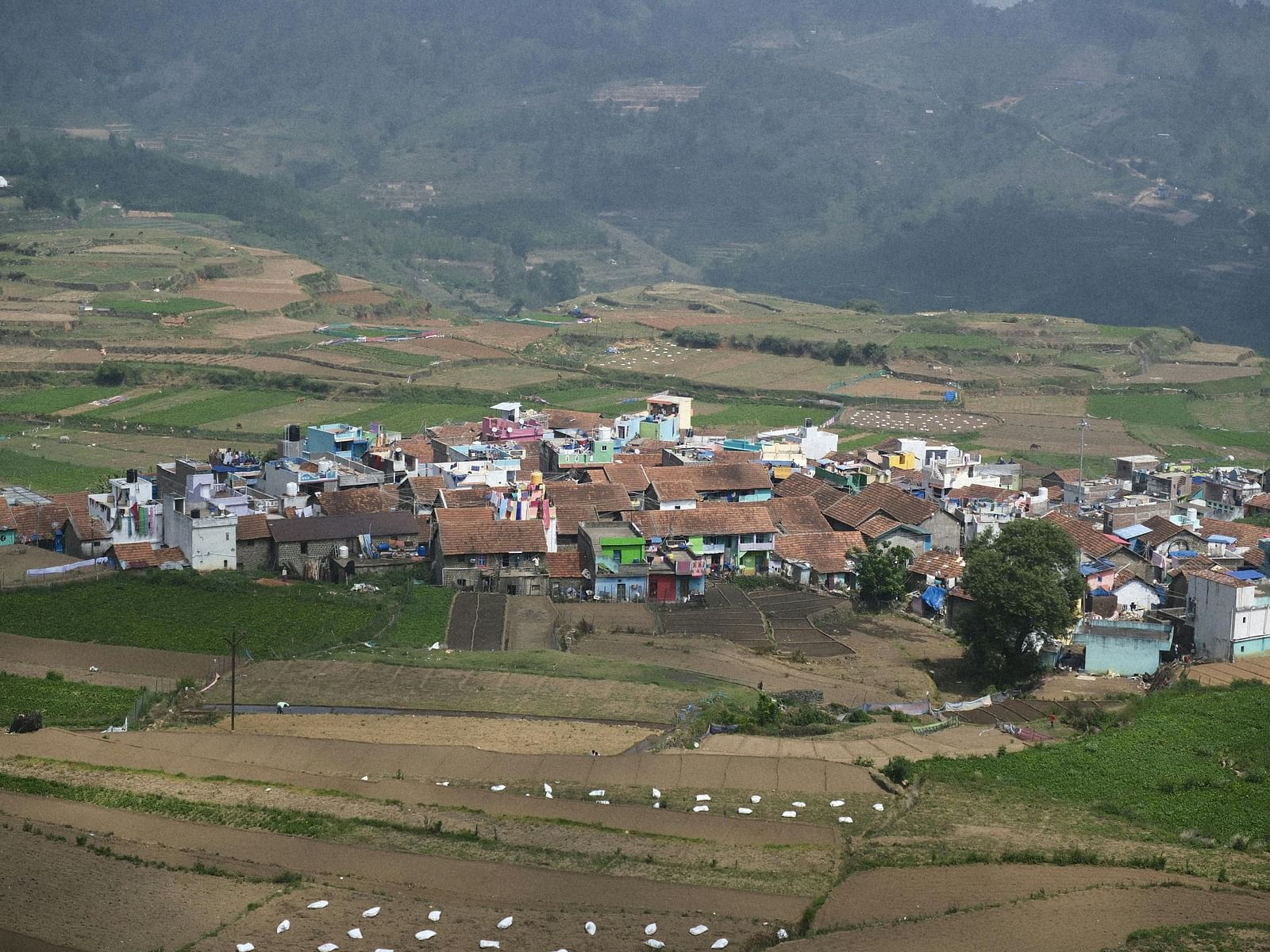 A village nestles in a valley surrounded by agricultural land.