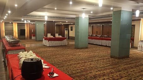 A warmly lit carpeted banquet hall of Lords Plaza Ankleshwar with buffet stations arranged along the sides of the room