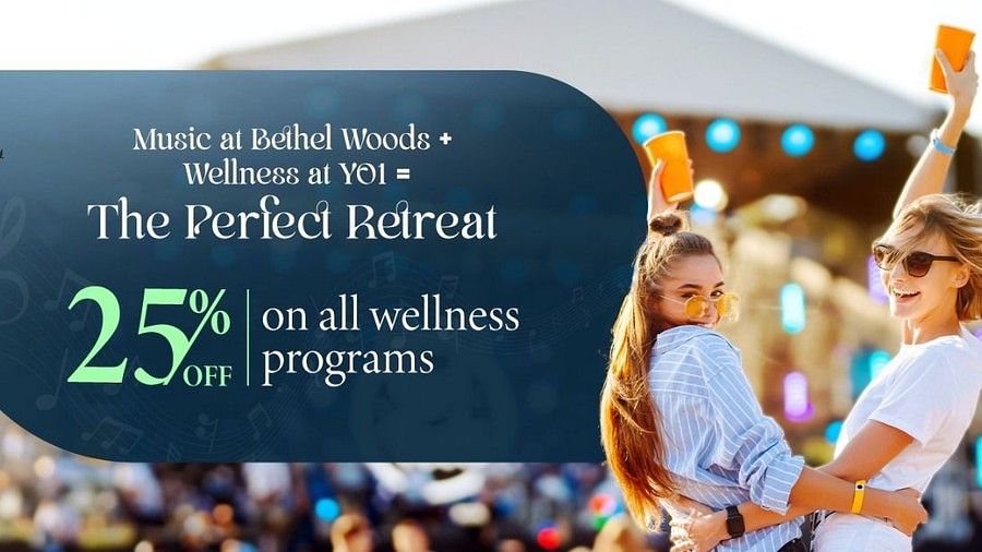 Two women enjoying a music festival with drinks, smiling and dancing, promoting a 25% discount on YO1 wellness programs near Bethel Woods.