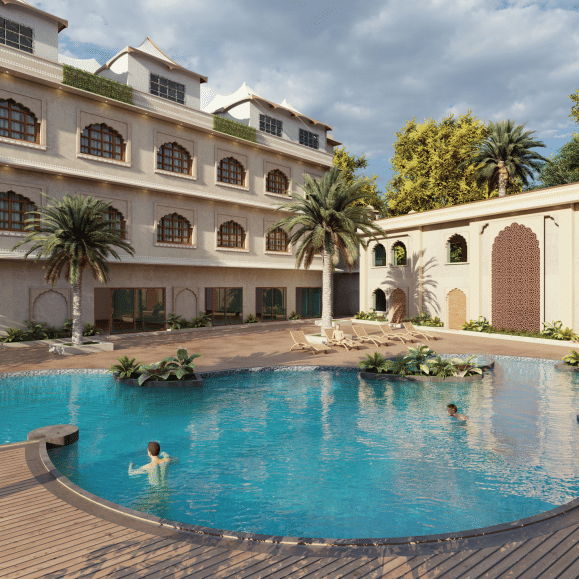 A wide view of a curved swimming pool in the foreground, with a multi storey building featuring arched balconies in the background, and paved deck areas with a person in the water, shown as an architectural visualisation at Ananta Elite Bharatpur.