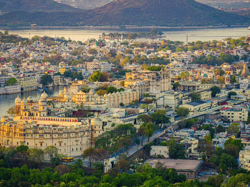 Aerial view of the city of Udaipur with the City Palace in the foreground and Lake Pichola in the backdrop.