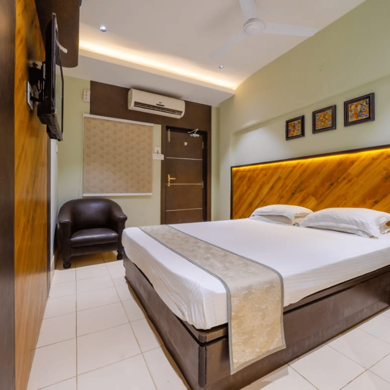 Spacious bedroom with a double bed, wall arts, an A/C, a seating area, and modern lighting – Hotel Dolphin Puri