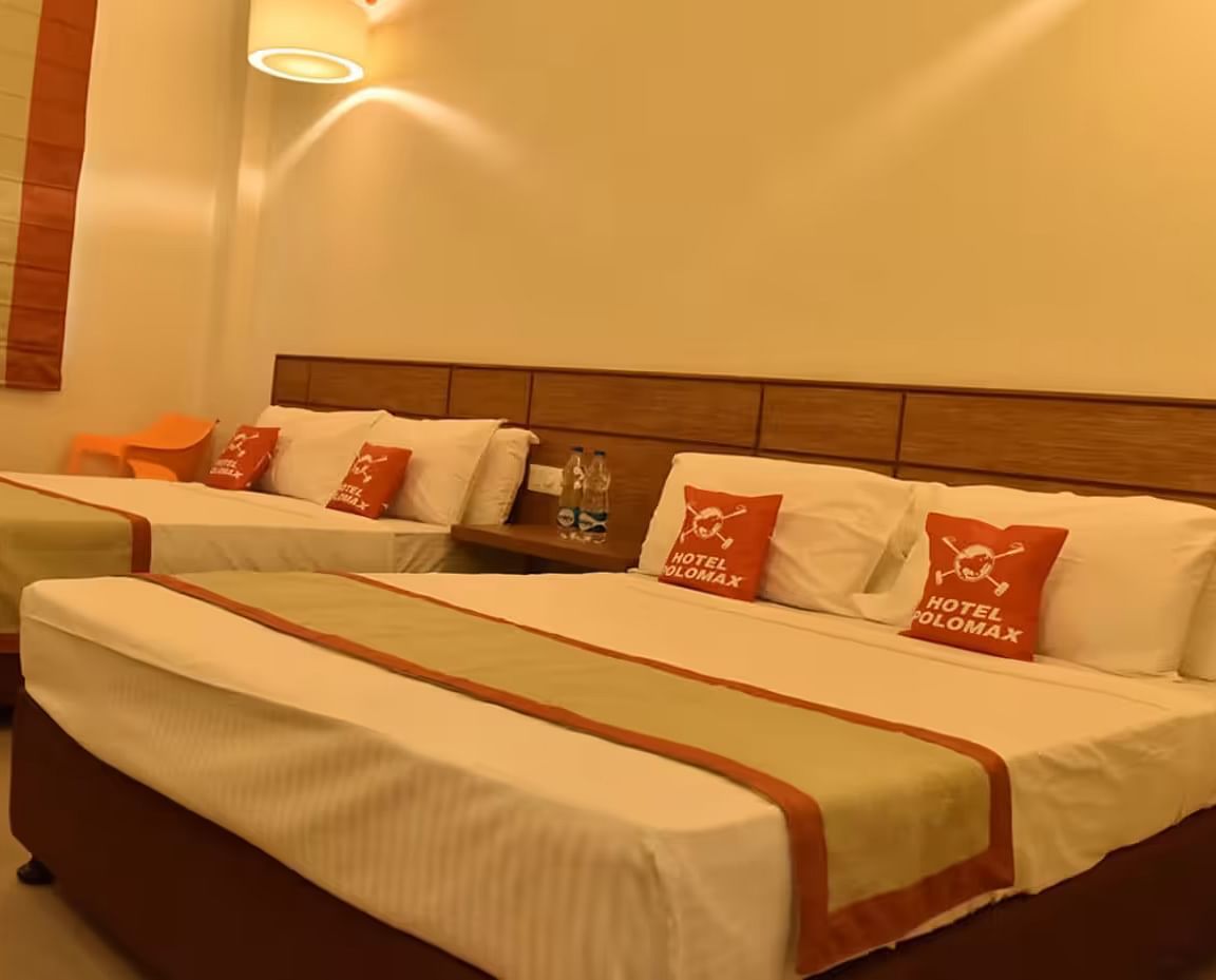 View of a hotel room with multiple beds, soft lighting, and cosy interiors - Max Hotel Prayagraj.