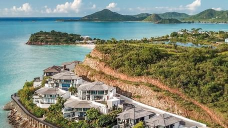 Aerial view of Tamarind Hills Resort and Villas on the coast of Antigua, nestled between lush hills and the turquoise waters of the Caribbean Sea.