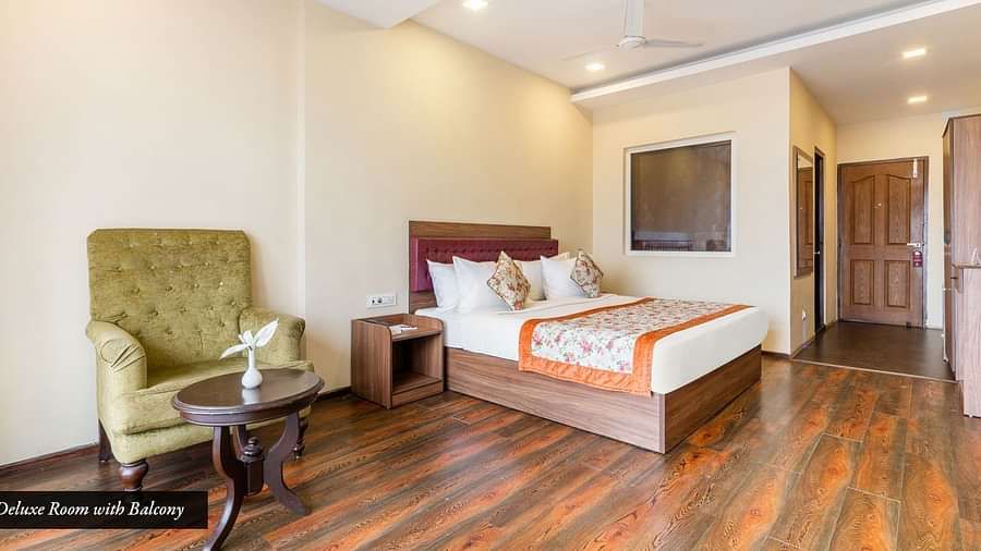 Deluxe room at Summit Barsana Resort & Spa, Kalimpong with a double bed and a sofa chair