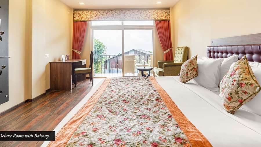 Deluxe room at Summit Barsana Resort & Spa, Kalimpong with a double bed and French windows