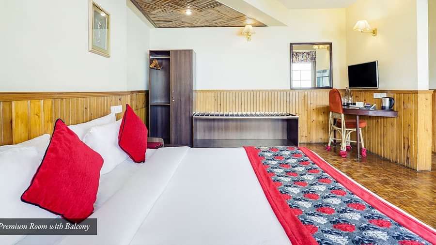 A side view of a bed in the room that has a TV, work desk, and a chair | Summit Newa Regency & Spa, Pelling