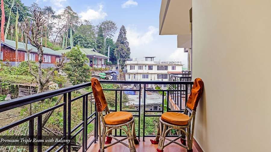 A side view of two chairs placed in a balcony that has a view of greenery | Summit Newa Regency & Spa, Pelling