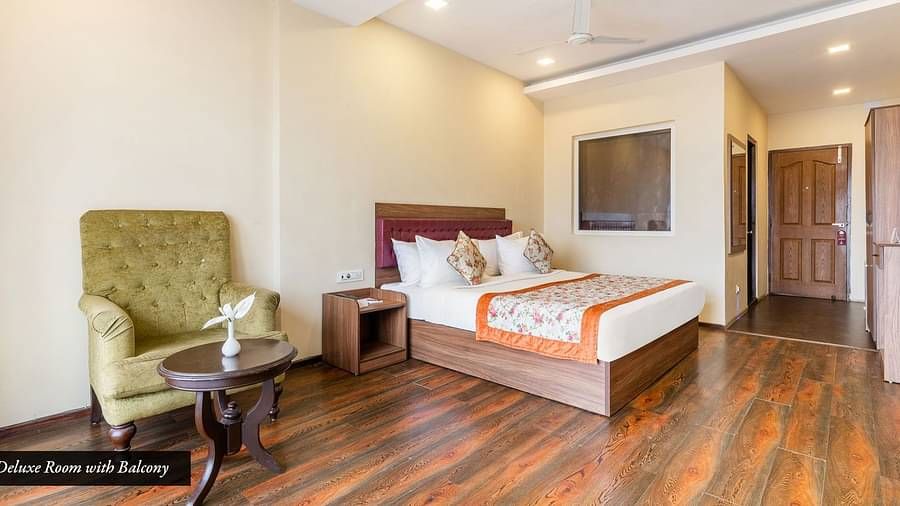 Deluxe room at Summit Barsana Resort & Spa, Kalimpong with a double bed and a sofa chair