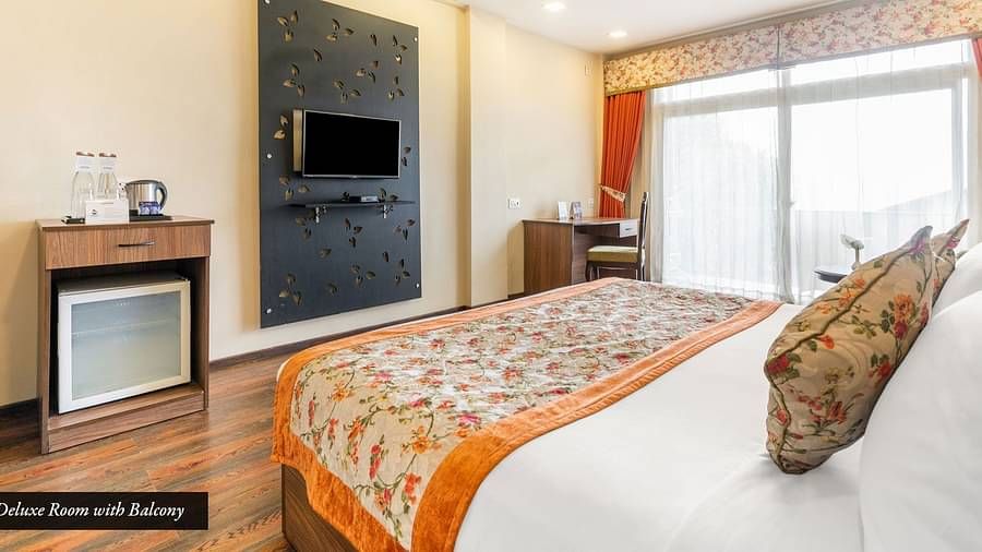 Deluxe room at Summit Barsana Resort & Spa, Kalimpong with a double bed and a television