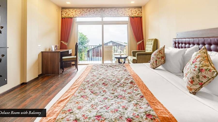 Deluxe room at Summit Barsana Resort & Spa, Kalimpong with a double bed and French windows