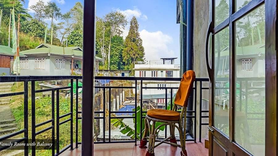 A side view of a chair placed in a balcony with a view of greenery | Summit Newa Regency & Spa, Pelling
